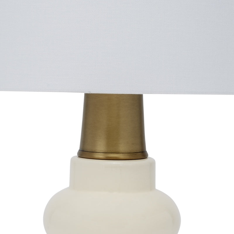 Cream ceramic table lamp base with brass top and white linen shade edge