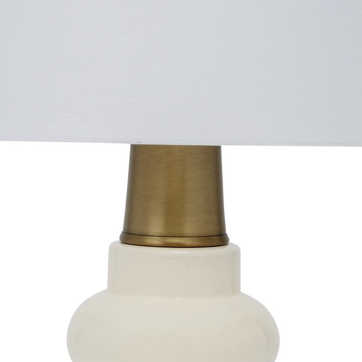 Cream ceramic table lamp base with brass top and white linen shade edge
