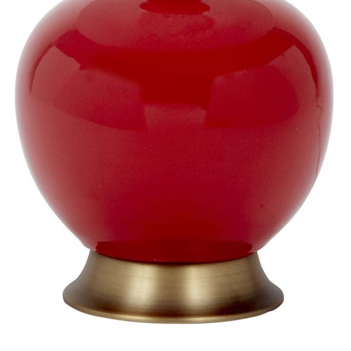 Red ceramic table lamp with gold-toned base, glossy round bottom detail
