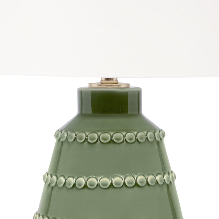 Green ceramic lamp base with beaded rings and brass-toned top hardware under white shade.