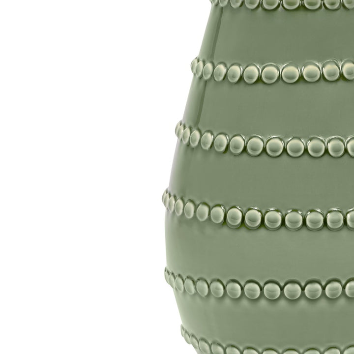 Green ceramic lamp base with stacked beaded rows and glossy finish, shade edge cropped.