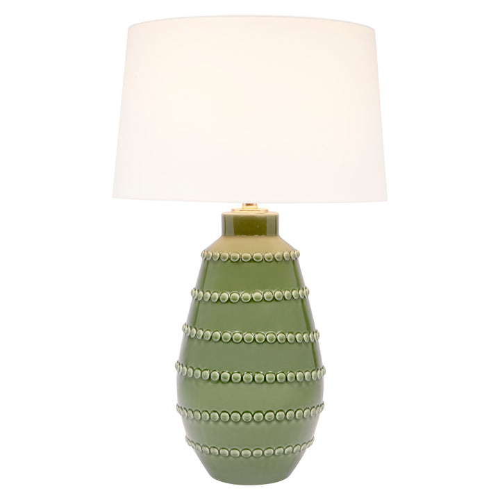 Green ceramic table lamp with white linen drum shade and stacked beaded bands on base.