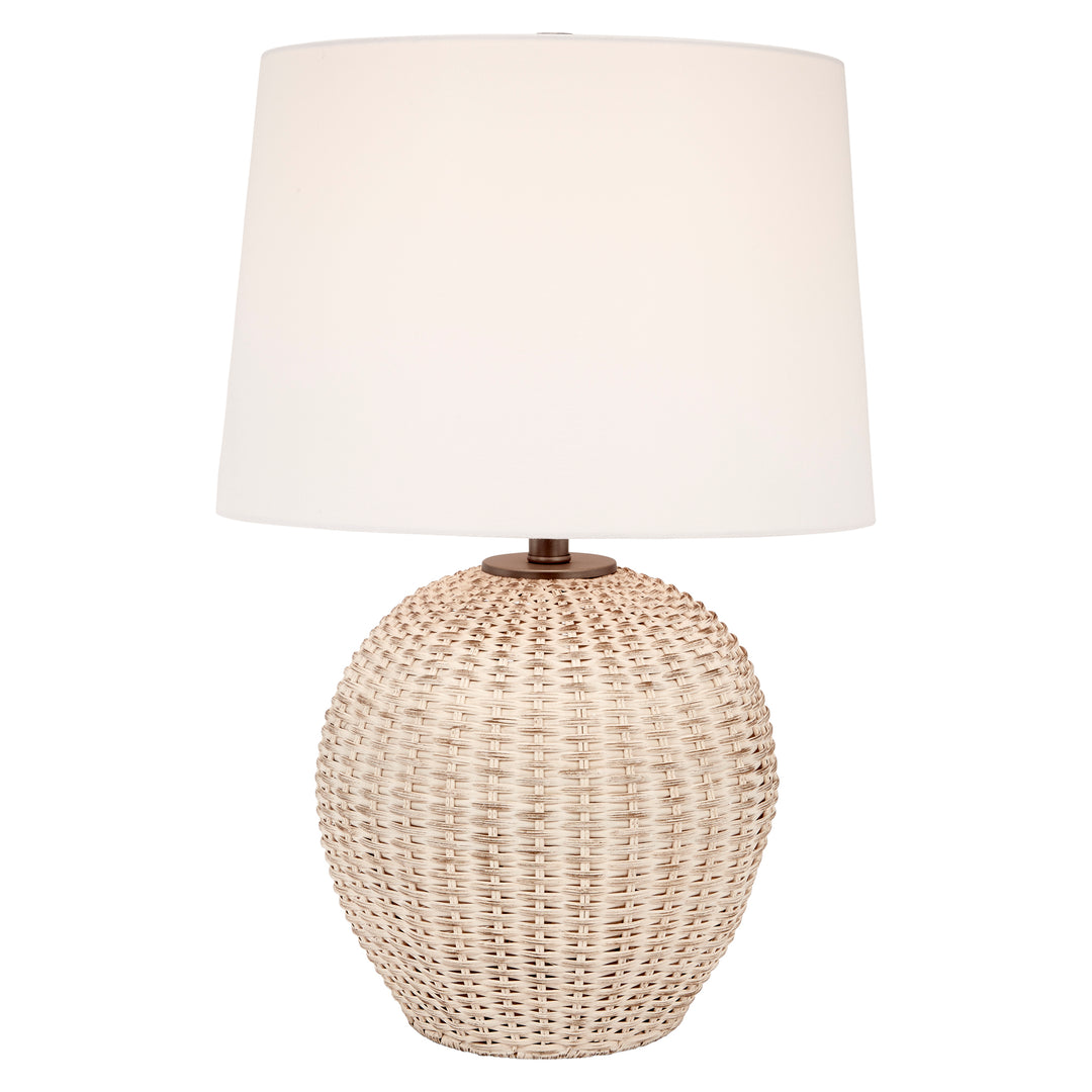Table lamp with white linen drum shade atop rounded woven rattan body