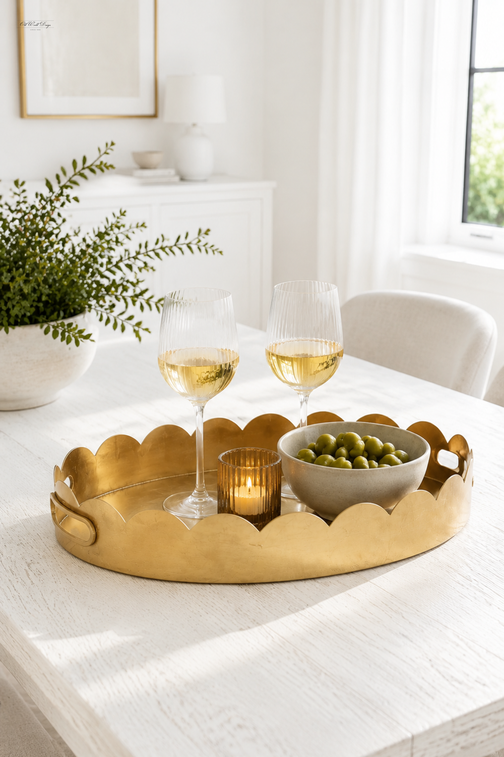 Gold oval gold-leaf tray with scalloped edge and cutout handles on a table.