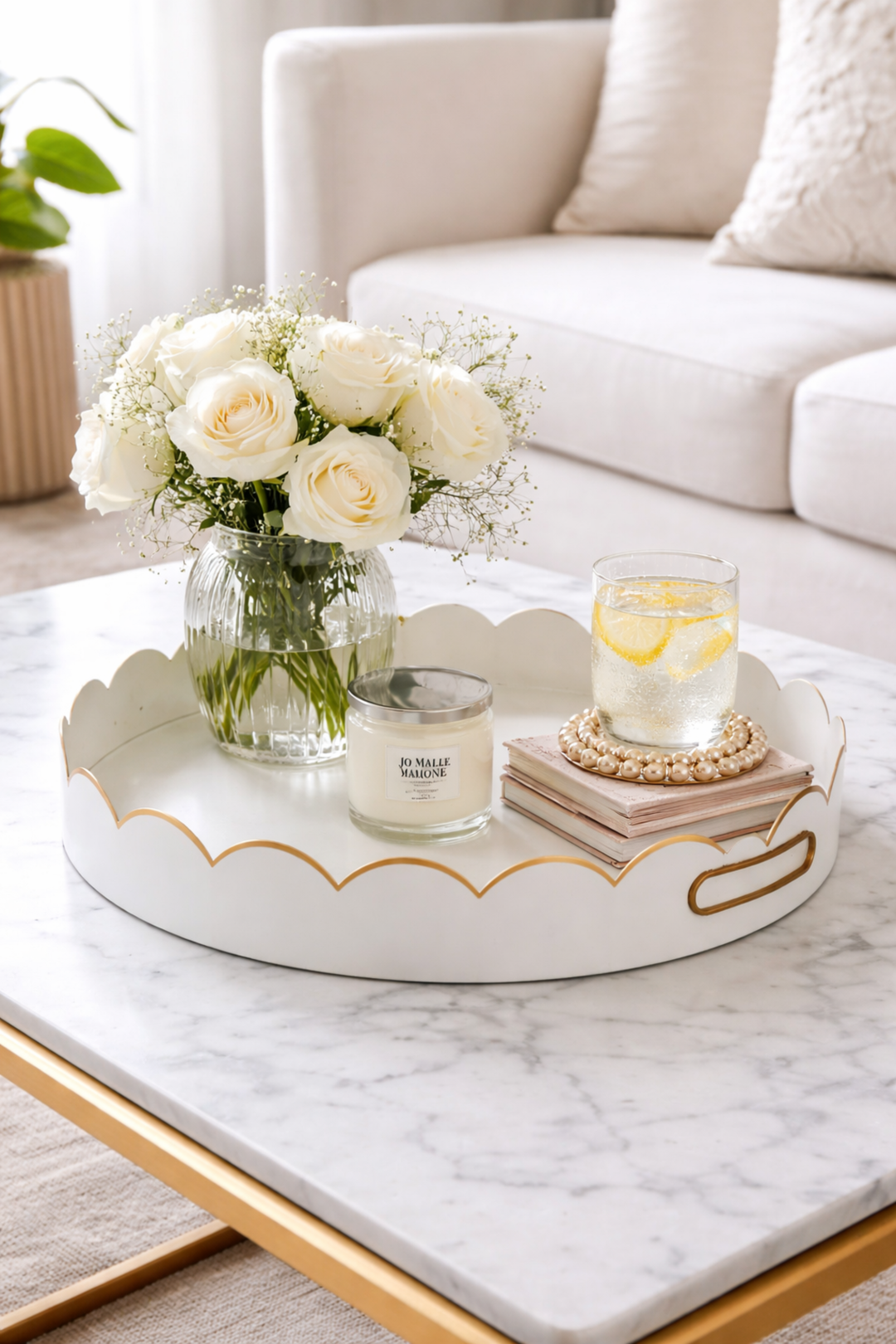 Decorative tray with flowers, candle, and glass on a marble surface