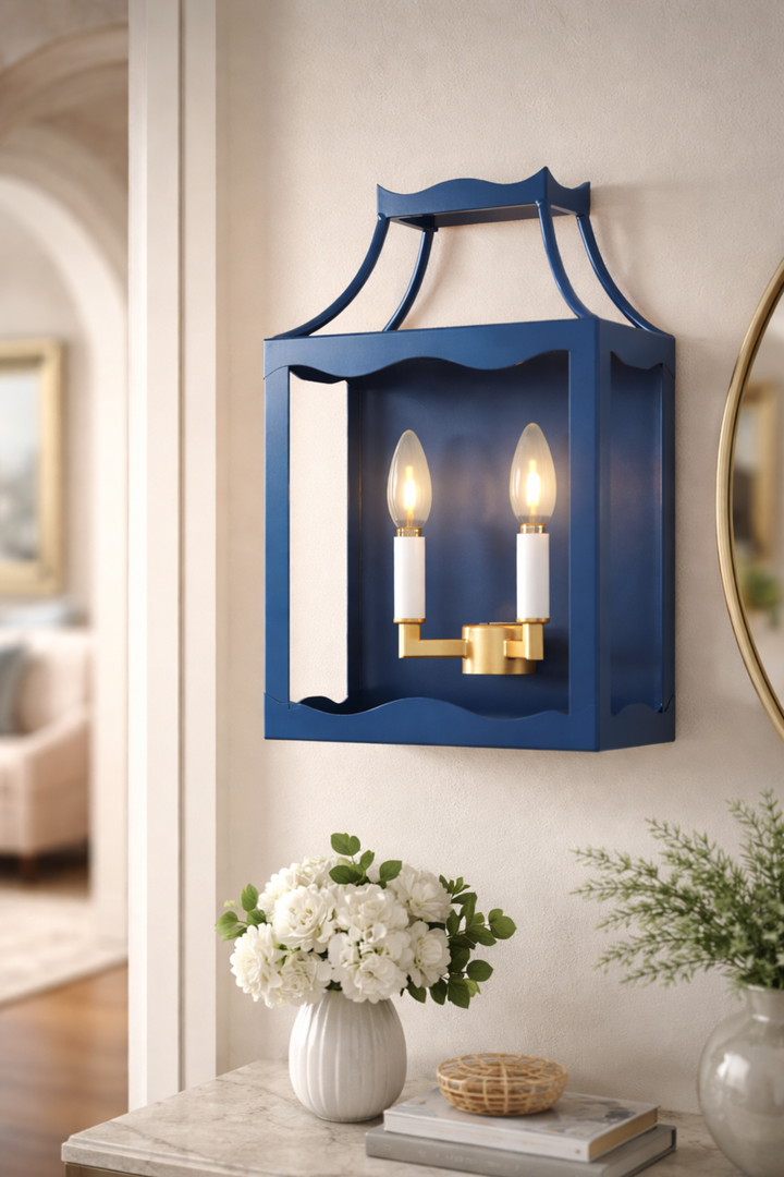 Blue wall sconce with two lights on a neutral wall, with decor items below.