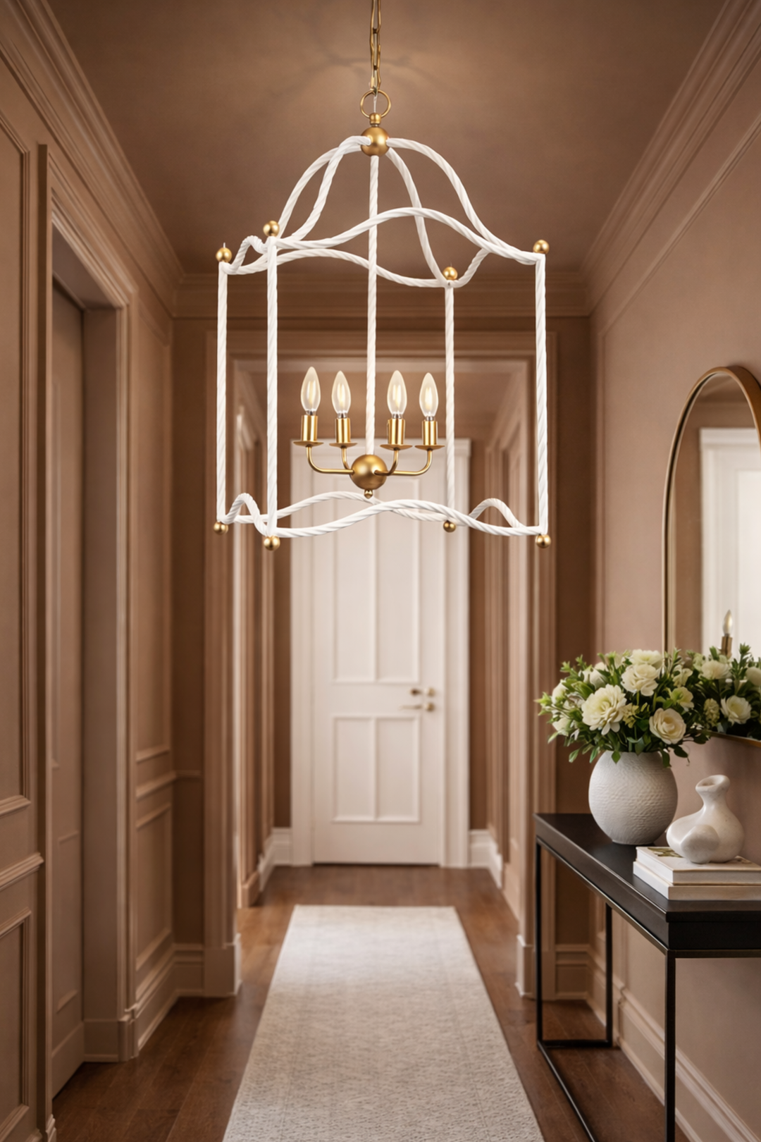 Decorative chandelier hanging in a hallway with a mirror and flowers on a table.