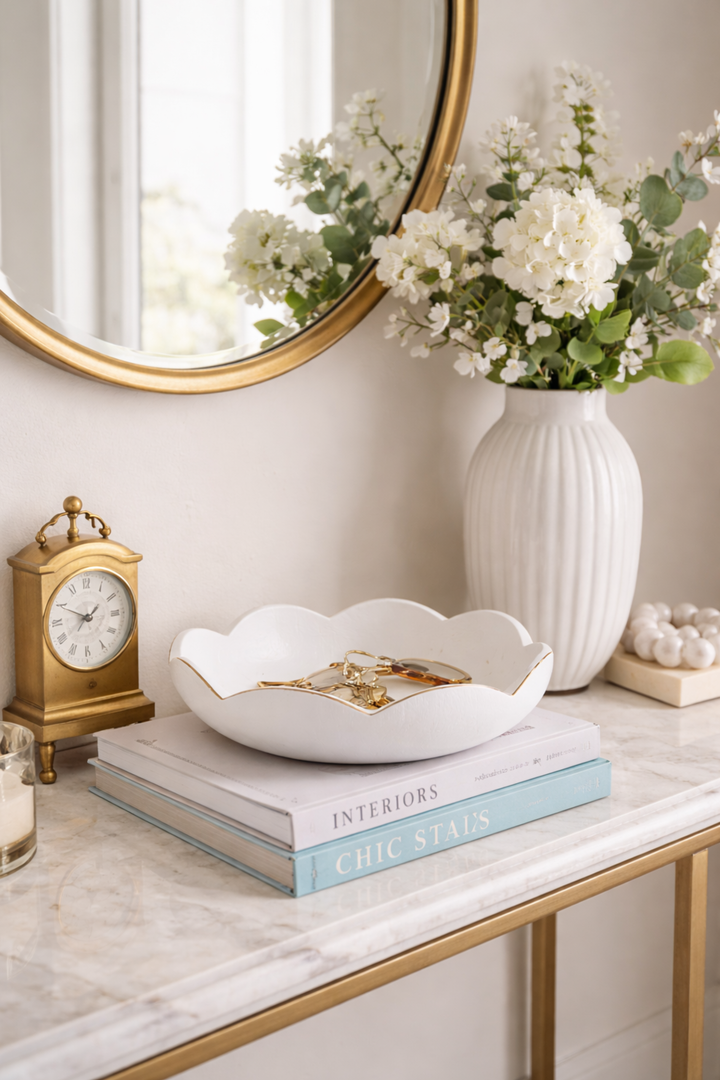 Decorative setup with a vase of flowers, books, and a clock on a marble surface.