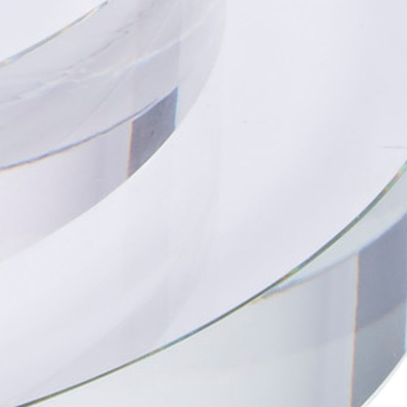 Large round clear crystal riser, close-up of curved edge over reflective supports