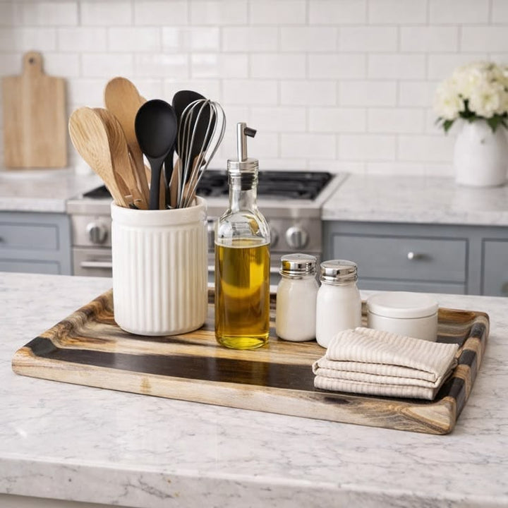 Kitchen counter with utensils, oil bottle, and towels on a wooden tray