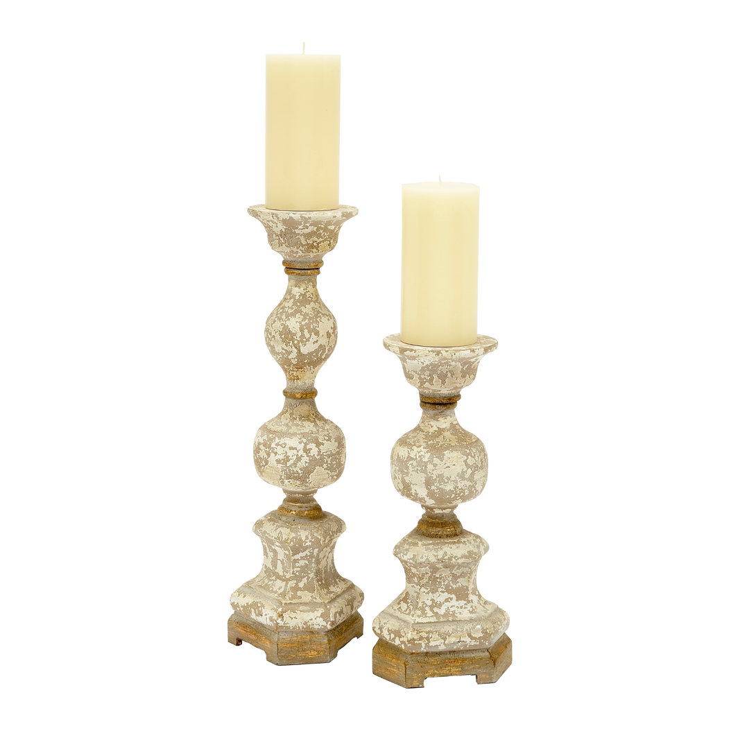Set of two distressed antique-style pillar candle holders with textured cream finish and rustic wood base on white background