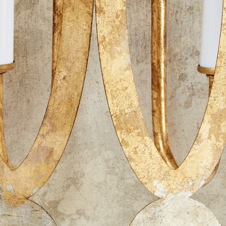 Aged gold metal wall sconce close-up of ornate oval design and curved center arm