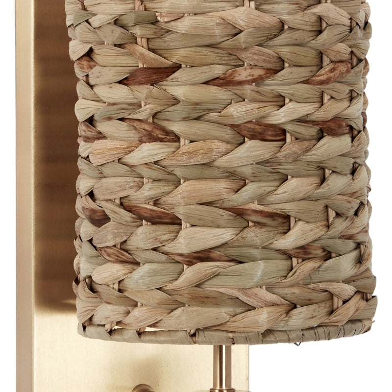 Gold wall sconce with woven water hyacinth shade and brass-toned mounting stem